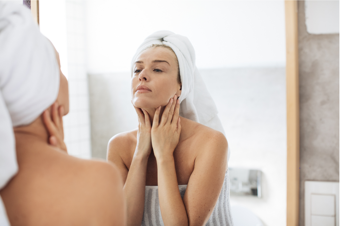 Dr. Pen Australia woman looking in mirror and applying a retinol anti-ageing serum 