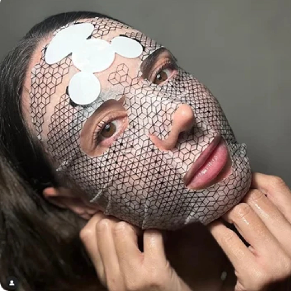 Woman wearing Celexo Galvanic Microcurrent Mask with graphene hexagon pattern and attached ultra-thin battery during facial treatment