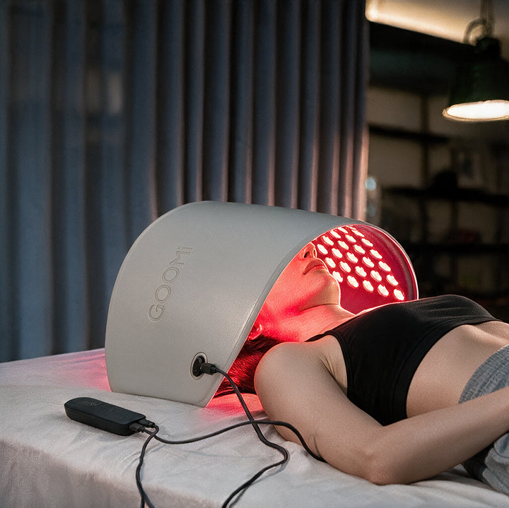 Woman using the GOOMi 3D Silicone LED Light Therapy Mask with red light while lying down