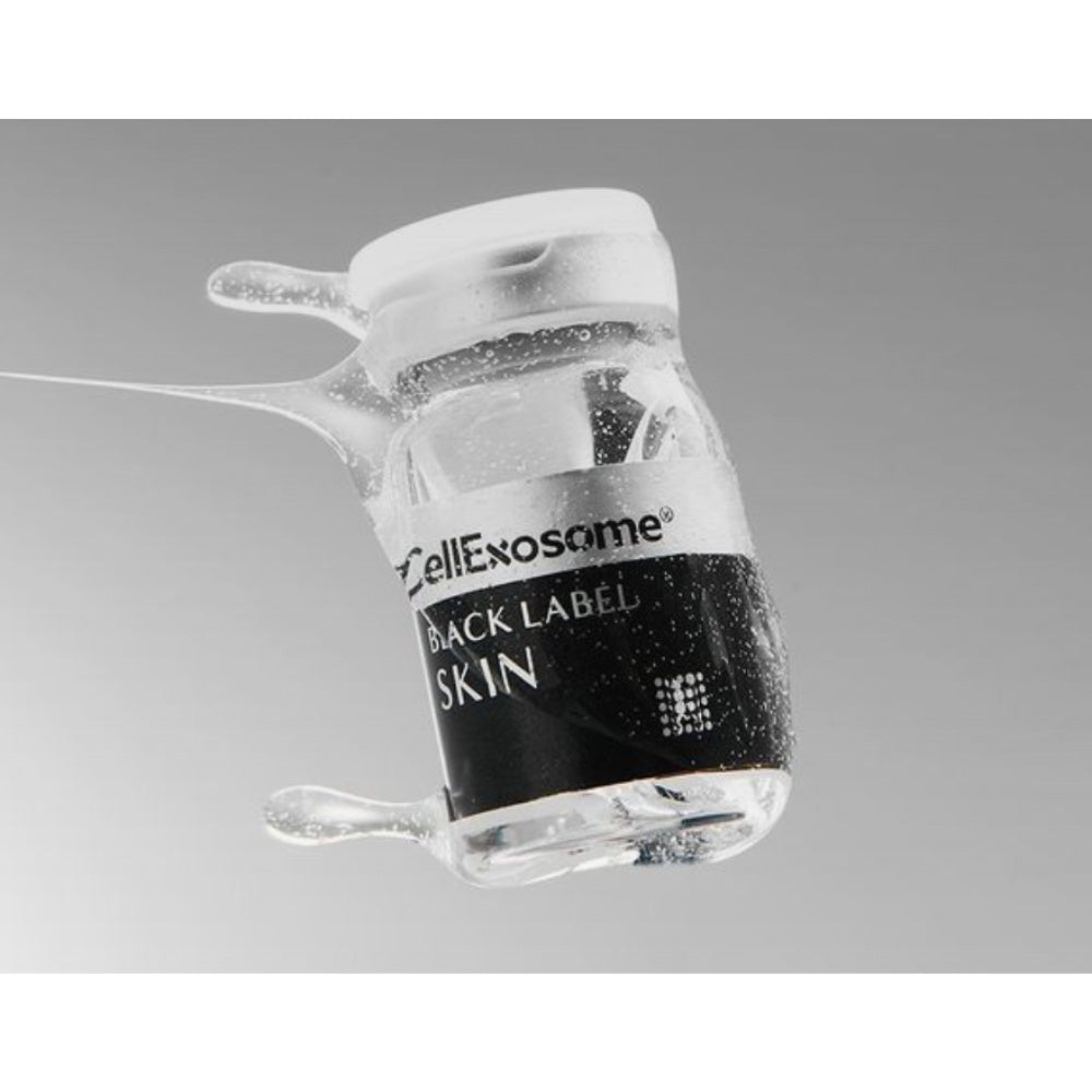 Close-up of a CellExosome BLACK LABEL Skin vial surrounded by serum droplets, highlighting the professional exosome skin regeneration treatment and premium skincare formulation.