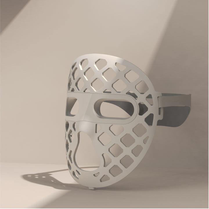 A white mesh-designed mask, the Peachaboo Glo Aurora, featuring LED light therapy technology for skin rejuvenation.