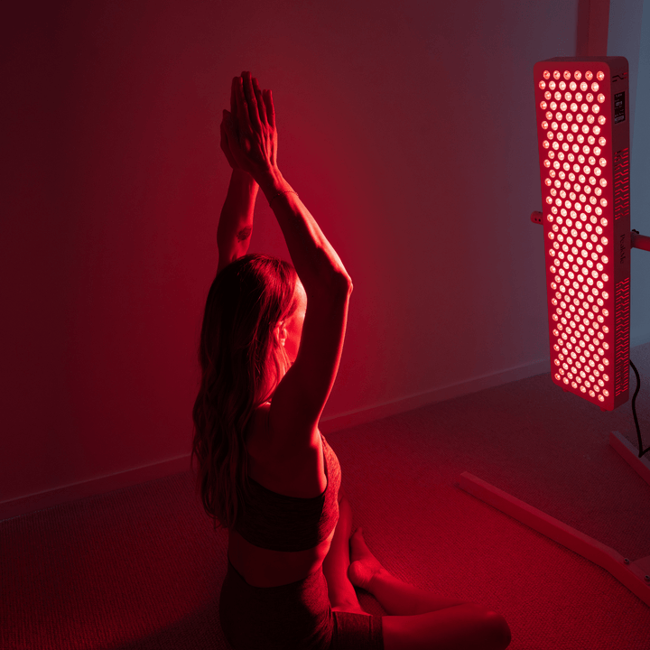 A woman bathing in a red light therapy PeakMe PRO using Panel Horizontal Stand by PeakMe 