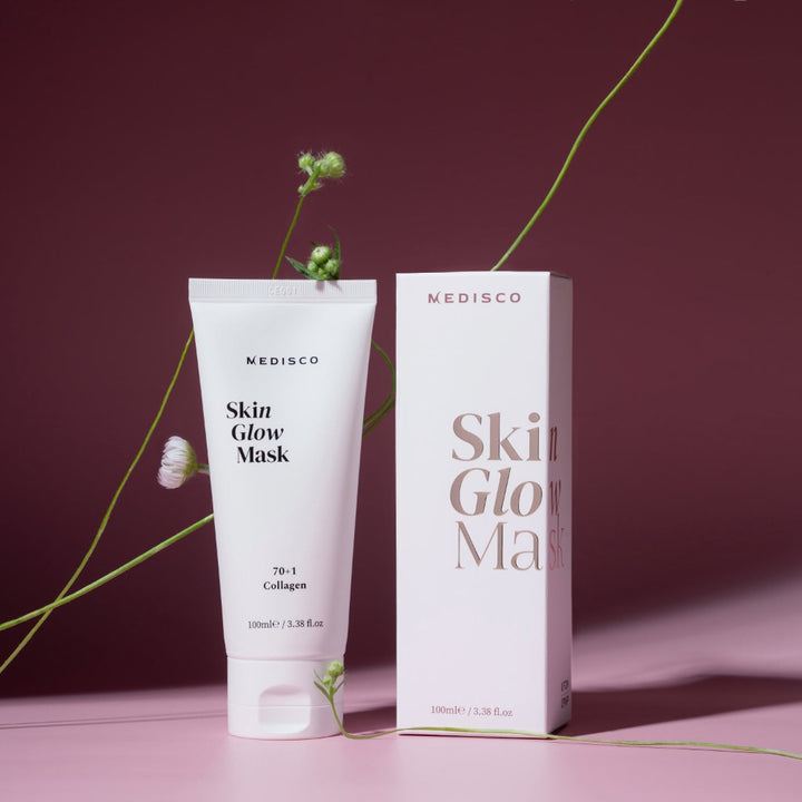 Medisco SkinGlow PDRN Collagen Mask tube and box styled with flowers on a burgundy backdrop