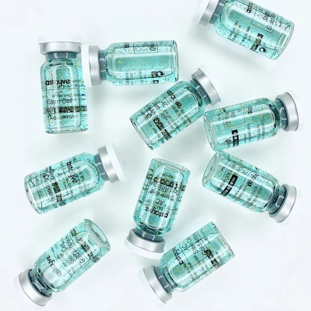 Multiple AC Stem Cell Gold Ampoule vials lying on a light gray background