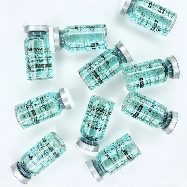 Multiple AC Stem Cell Gold Ampoule vials lying on a light gray background